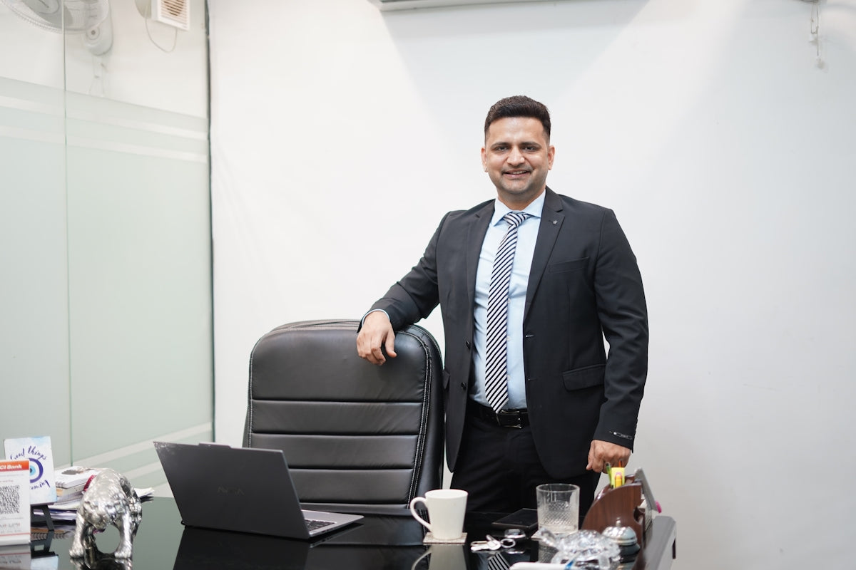 A man in a suit stands behind an office desk.